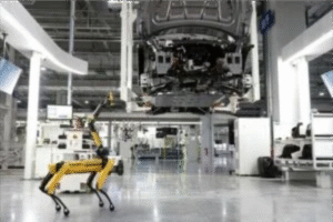 Robô quadrúpede amarelo em uma linha de montagem automatizada com carro suspenso.